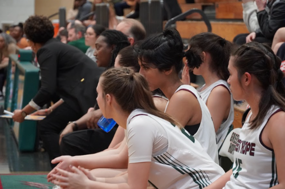 Players on the women’s basketball team sit together spectating their teammates